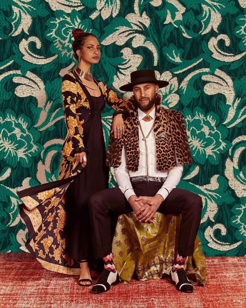 man and woman posing in front of a green wall