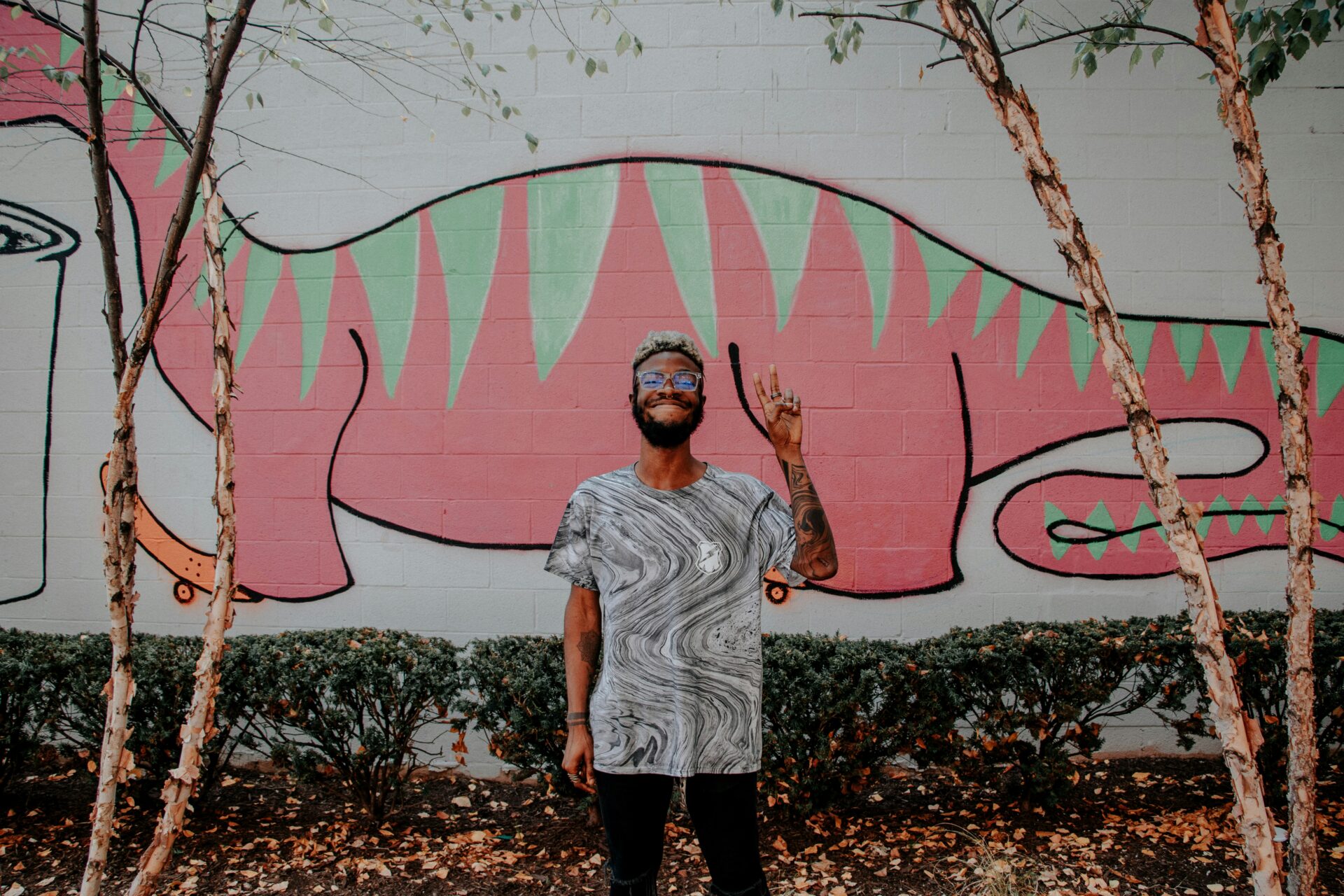 A man standing in front of a pink mural.